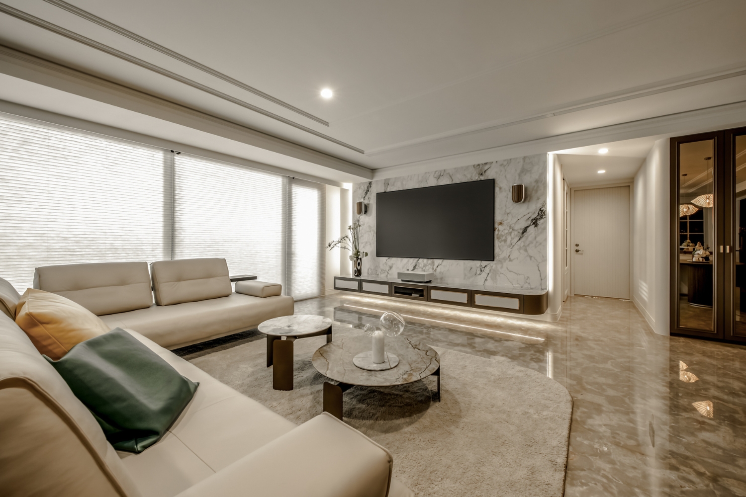 現代風客廳裝潢選用大理石地磚與電視牆，搭配莫蘭迪色系抱枕與質感圓形茶几