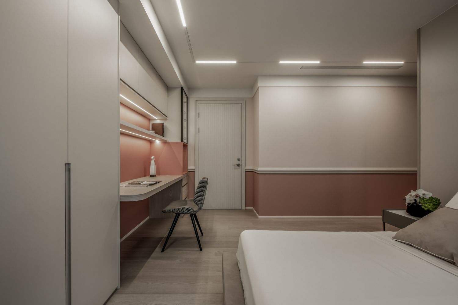結合粉嫩色調的臥房內，矽酸鈣板天花板嵌入極簡線性燈帶提供柔和光源，平整的板材表面有效修飾樑柱，不僅提升視覺高度，更讓天花板維修路徑與照明配置在不破壞美觀的前提下，達到空間設計與機能結構的完美平衡