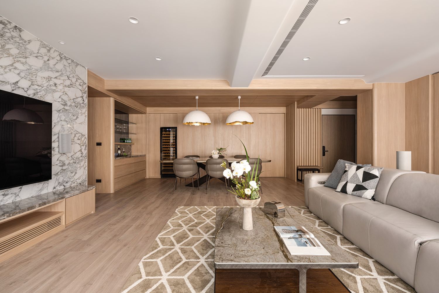 充滿暖木質感的客餐廳展現木作與白色矽酸鈣板天花板的拼接魅力，吊隱式空調精準設置線型出風口，將天花板維修所需的管路系統巧妙藏於優美的異材質設計中，為現代家庭構築出層次分明且符合防火耐燃標準的安全生活空間